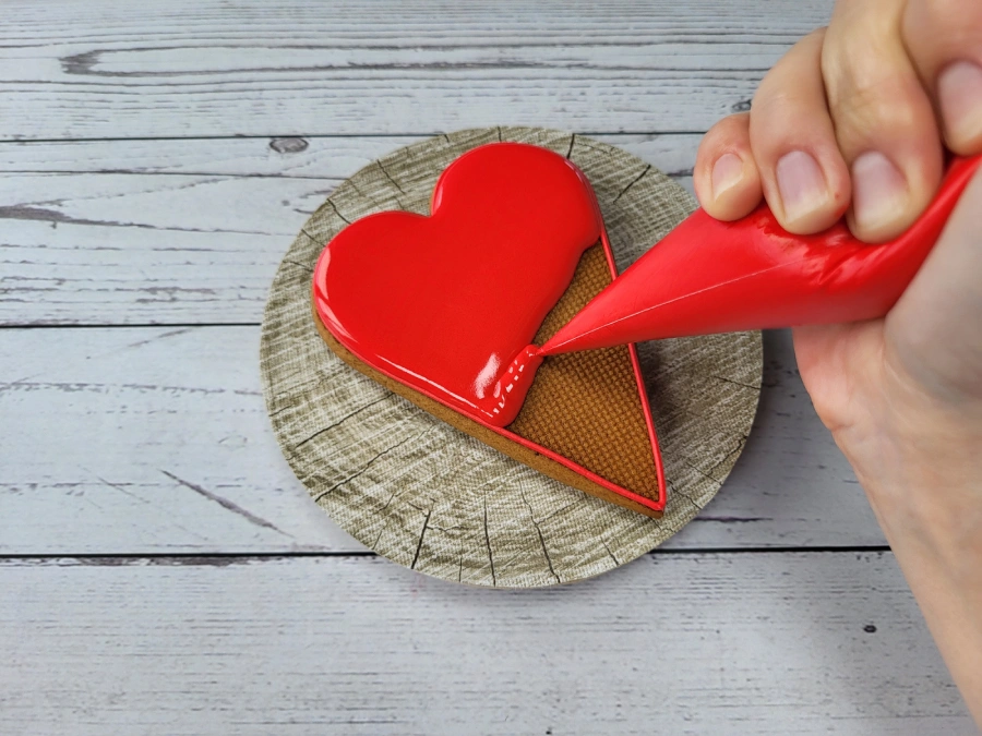 Piping cone controlling royal icing flow during cookie decorating