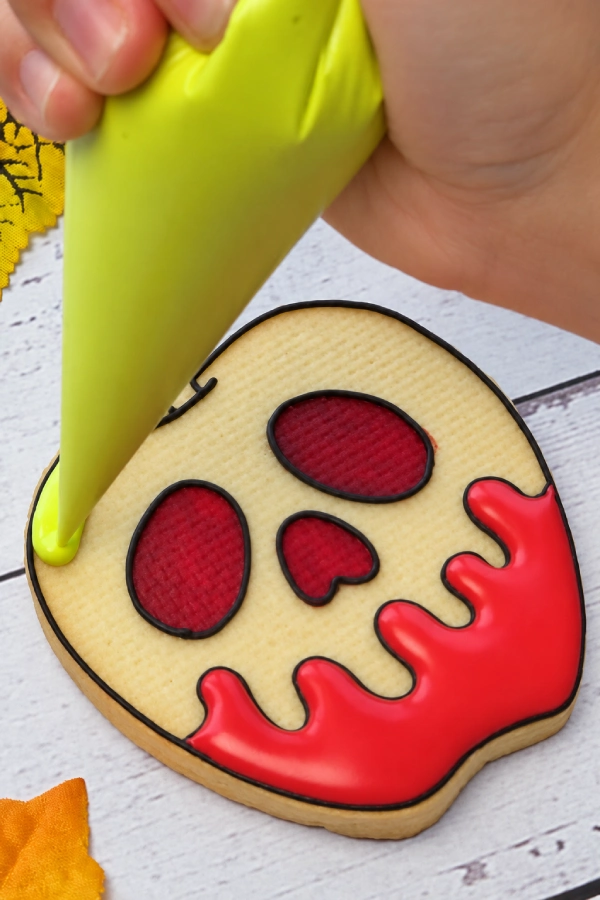 Piping royal icing onto a decorated cookie